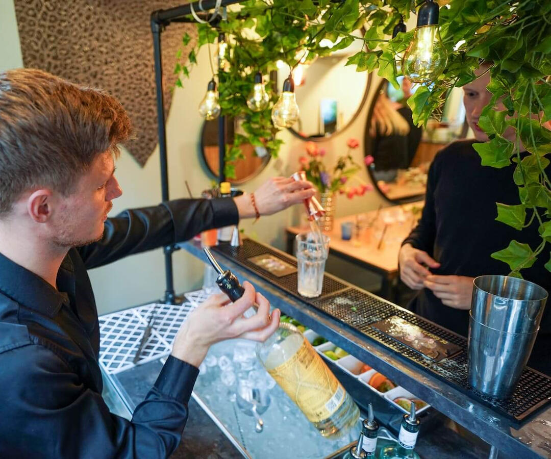 Persoonlijke service: Jouw cocktail, direct geserveerd Cocktailshaker serveert een vers bereide cocktail aan een gast tijdens een feest in Rotterdam. Persoonlijke service en gastvrijheid bij mobiele cocktailbar op locatie in Zuid-Holland.
